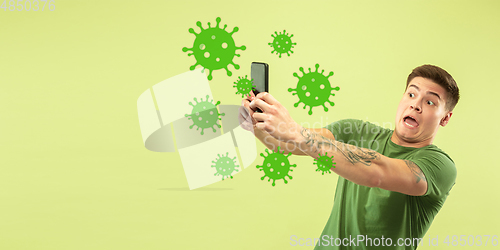 Image of Young man using phone, watching news of coronavirus spreading and worldwide cases, shocked and sad