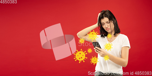 Image of Young woman using phone, watching news of coronavirus spreading and worldwide cases, shocked and sad