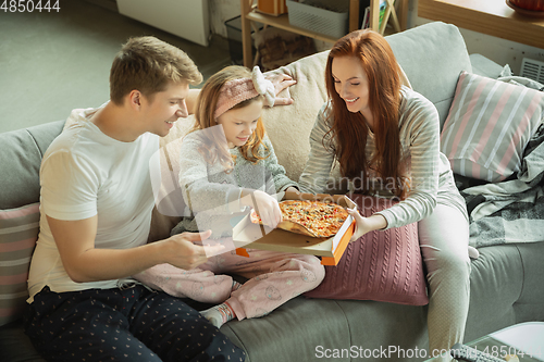 Image of Family spending nice time together at home, looks happy and cheerful, eating pizza