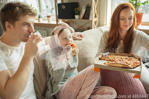 Image of Family spending nice time together at home, looks happy and cheerful, eating pizza