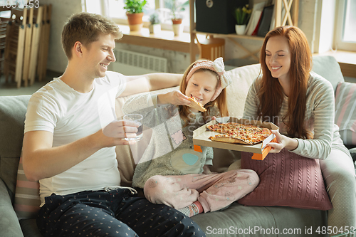 Image of Family spending nice time together at home, looks happy and cheerful, eating pizza