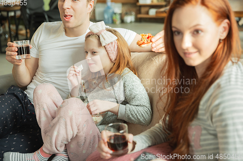 Image of Family spending nice time together at home, looks happy and cheerful, eating pizza