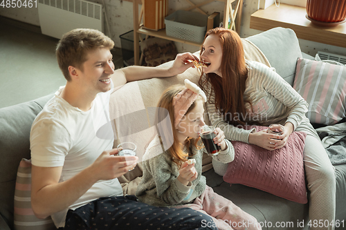 Image of Family spending nice time together at home, looks happy and cheerful, eating pizza