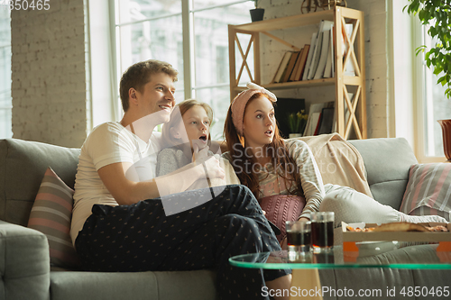 Image of Family spending nice time together at home, looks happy and cheerful, eating pizza