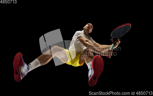 Image of Young caucasian tennis player in action, motion isolated on black background, look from the bottom. Concept of sport, movement, energy and dynamic.