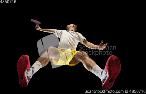 Image of Young caucasian tennis player in action, motion isolated on black background, look from the bottom. Concept of sport, movement, energy and dynamic.