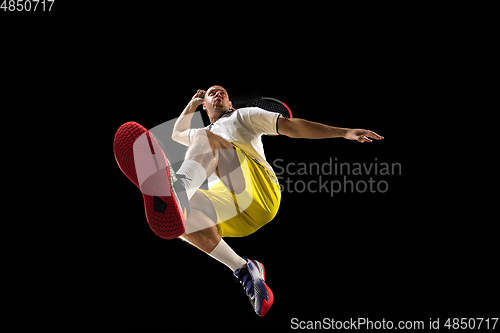 Image of Young caucasian tennis player in action, motion isolated on black background, look from the bottom. Concept of sport, movement, energy and dynamic.