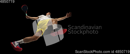 Image of Young caucasian tennis player in action, motion isolated on black background, look from the bottom. Concept of sport, movement, energy and dynamic.