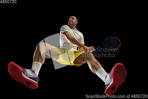 Image of Young caucasian tennis player in action, motion isolated on black background, look from the bottom. Concept of sport, movement, energy and dynamic.