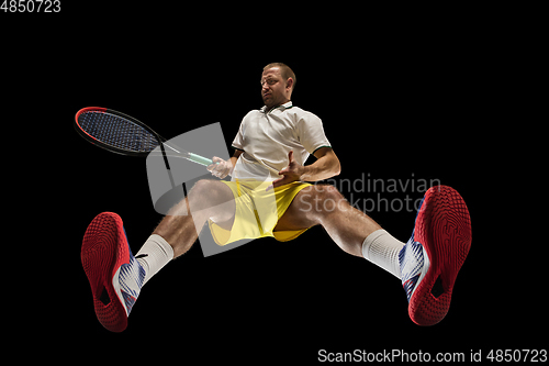 Image of Young caucasian tennis player in action, motion isolated on black background, look from the bottom. Concept of sport, movement, energy and dynamic.