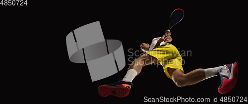 Image of Young caucasian tennis player in action, motion isolated on black background, look from the bottom. Concept of sport, movement, energy and dynamic.