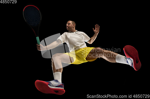 Image of Young caucasian tennis player in action, motion isolated on black background, look from the bottom. Concept of sport, movement, energy and dynamic.