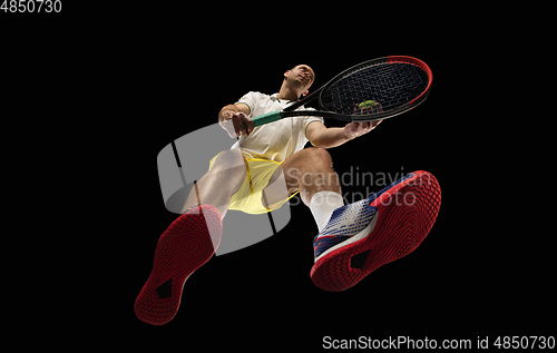 Image of Young caucasian tennis player in action, motion isolated on black background, look from the bottom. Concept of sport, movement, energy and dynamic.