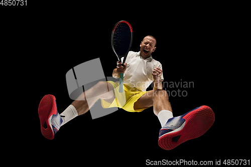 Image of Young caucasian tennis player in action, motion isolated on black background, look from the bottom. Concept of sport, movement, energy and dynamic.