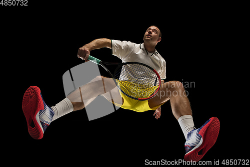 Image of Young caucasian tennis player in action, motion isolated on black background, look from the bottom. Concept of sport, movement, energy and dynamic.