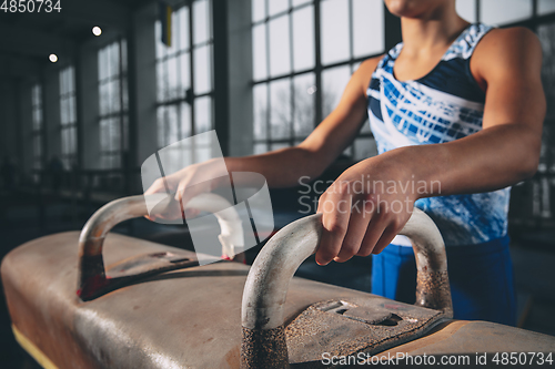 Image of Little male gymnast training in gym, flexible and active. Caucasian fit little boy, athlete in sportswear practicing in exercises for strength, balance.