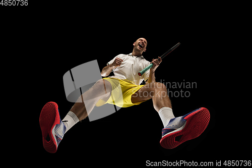 Image of Young caucasian tennis player in action, motion isolated on black background, look from the bottom. Concept of sport, movement, energy and dynamic.