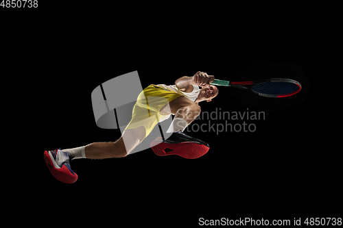 Image of Young caucasian tennis player in action, motion isolated on black background, look from the bottom. Concept of sport, movement, energy and dynamic.