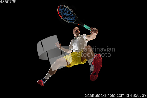 Image of Young caucasian tennis player in action, motion isolated on black background, look from the bottom. Concept of sport, movement, energy and dynamic.