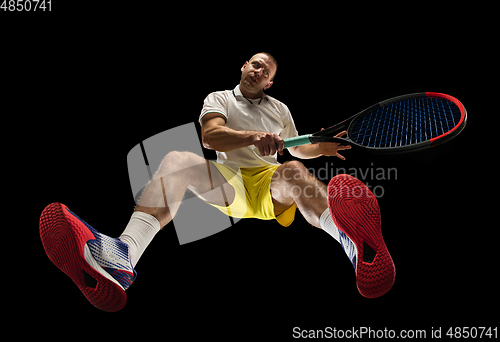 Image of Young caucasian tennis player in action, motion isolated on black background, look from the bottom. Concept of sport, movement, energy and dynamic.