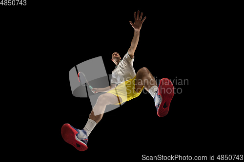 Image of Young caucasian tennis player in action, motion isolated on black background, look from the bottom. Concept of sport, movement, energy and dynamic.