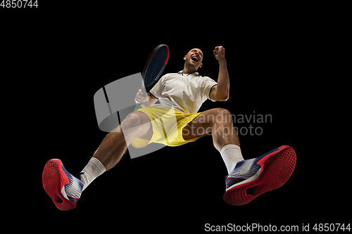 Image of Young caucasian tennis player in action, motion isolated on black background, look from the bottom. Concept of sport, movement, energy and dynamic.