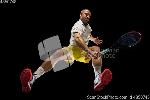 Image of Young caucasian tennis player in action, motion isolated on black background, look from the bottom. Concept of sport, movement, energy and dynamic.