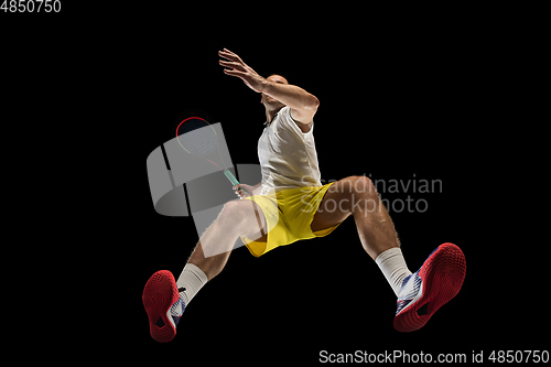 Image of Young caucasian tennis player in action, motion isolated on black background, look from the bottom. Concept of sport, movement, energy and dynamic.