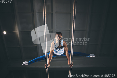 Image of Little male gymnast training in gym, flexible and active. Caucasian fit little boy, athlete in sportswear practicing in exercises for strength, balance.