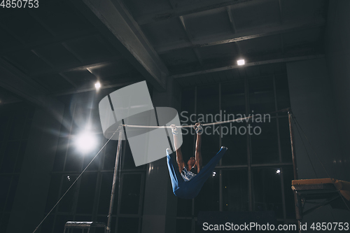 Image of Little male gymnast training in gym, flexible and active. Caucasian fit little boy, athlete in sportswear practicing in exercises for strength, balance.