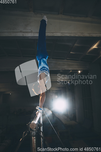 Image of Little male gymnast training in gym, flexible and active. Caucasian fit little boy, athlete in sportswear practicing in exercises for strength, balance.