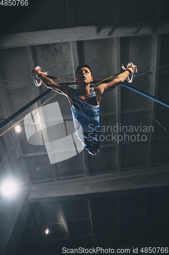 Image of Little male gymnast training in gym, flexible and active. Caucasian fit little boy, athlete in sportswear practicing in exercises for strength, balance.