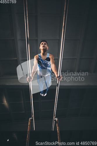 Image of Little male gymnast training in gym, flexible and active. Caucasian fit little boy, athlete in sportswear practicing in exercises for strength, balance.