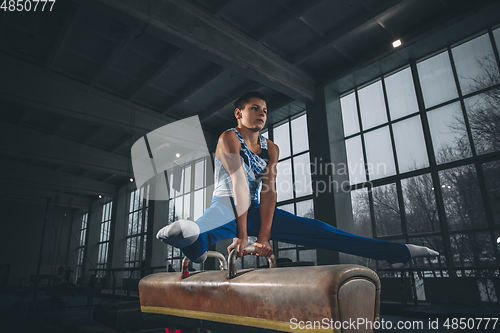 Image of Little male gymnast training in gym, flexible and active. Caucasian fit little boy, athlete in sportswear practicing in exercises for strength, balance.