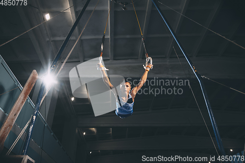 Image of Little male gymnast training in gym, flexible and active. Caucasian fit little boy, athlete in sportswear practicing in exercises for strength, balance.