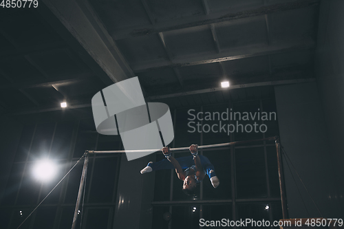 Image of Little male gymnast training in gym, flexible and active. Caucasian fit little boy, athlete in sportswear practicing in exercises for strength, balance.