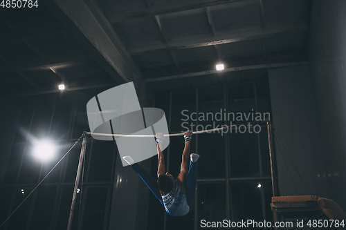 Image of Little male gymnast training in gym, flexible and active. Caucasian fit little boy, athlete in sportswear practicing in exercises for strength, balance.