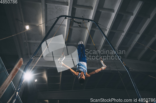 Image of Little male gymnast training in gym, flexible and active. Caucasian fit little boy, athlete in sportswear practicing in exercises for strength, balance.