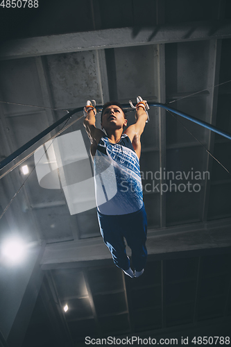 Image of Little male gymnast training in gym, flexible and active. Caucasian fit little boy, athlete in sportswear practicing in exercises for strength, balance.