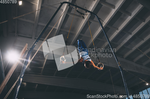 Image of Little male gymnast training in gym, flexible and active. Caucasian fit little boy, athlete in sportswear practicing in exercises for strength, balance.