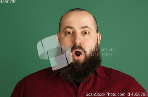 Image of Handsome caucasian man portrait isolated on green studio background with copyspace