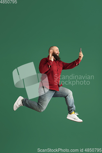 Image of Handsome caucasian man portrait isolated on green studio background with copyspace