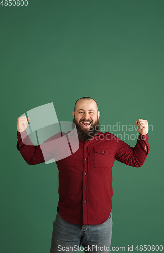 Image of Handsome caucasian man portrait isolated on green studio background with copyspace