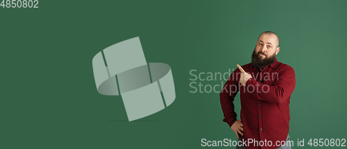 Image of Handsome caucasian man portrait isolated on green studio background with copyspace