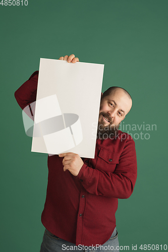 Image of Handsome caucasian man portrait isolated on green studio background with copyspace