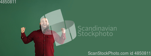 Image of Handsome caucasian man portrait isolated on green studio background with copyspace