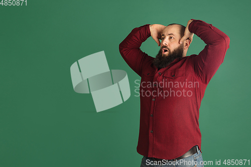 Image of Handsome caucasian man portrait isolated on green studio background with copyspace