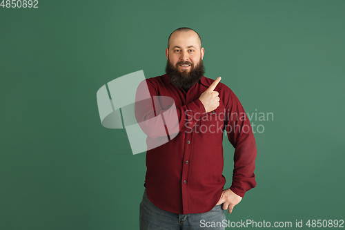 Image of Handsome caucasian man portrait isolated on green studio background with copyspace