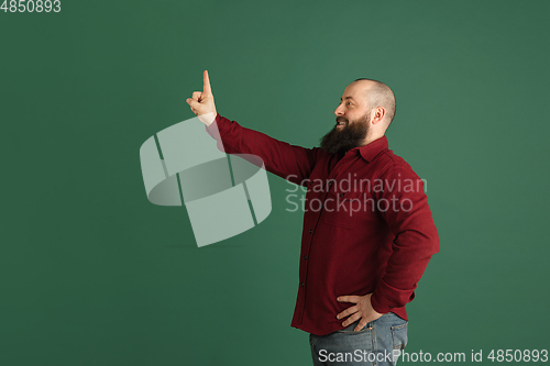 Image of Handsome caucasian man portrait isolated on green studio background with copyspace