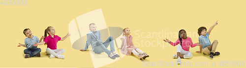 Image of Little and happy kids gesturing isolated on yellow studio background. Human emotions, facial expression concept
